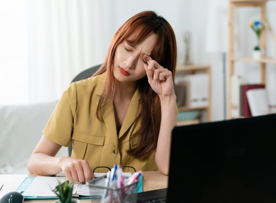 Front,Shot,Of,A,Tired,Korean,Female,Manager,Rubbing,Her